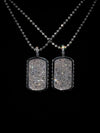 Two silver dog tag necklaces with sparkling clear stones, displayed against a solid black background.