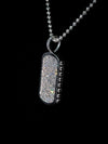 A silver-toned rectangular pendant necklace covered in sparkling clear stones, hanging from a matching silver ball chain against a solid black background.