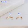 Two small gold open hoop earrings with clear teardrop-shaped stones, labeled LG and SM for stone size comparison, on a light marble-like surface.