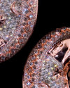 Close-up of rose gold jewelry featuring pavé-set clear stones, including crescent moon and star motifs, shown against a solid black background.