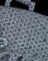 Close-up detail of a heavily pavé diamond handbag in silver-toned metal, showing the textured crystal surface and a large round diamond inset.