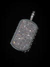 A rectangular dog tag pendant covered in sparkling clear crystals, featuring a muted sage green border and a matching crystal-embellished bail, set against a solid black background.