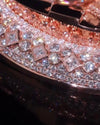 Close-up of a rose gold jewelry piece heavily embellished with clear pavé diamonds, featuring a row of square and round diamond accents.