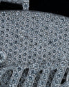 Extreme close-up of a heavily paved diamond clutch or purse surface, showing a dense pattern of round-cut stones in silver-toned metal against a dark background.