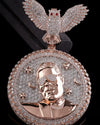 A large oval pendant featuring a rose gold portrait of a man wearing a diamond-encrusted visor, surrounded by stars, crescent moons, and a matching diamond-encrusted circular border. At the top is a winged owl figure also covered in diamonds, shown against a black background.